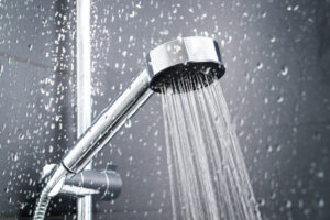 Water running from chrome shower head in modern bathroom.