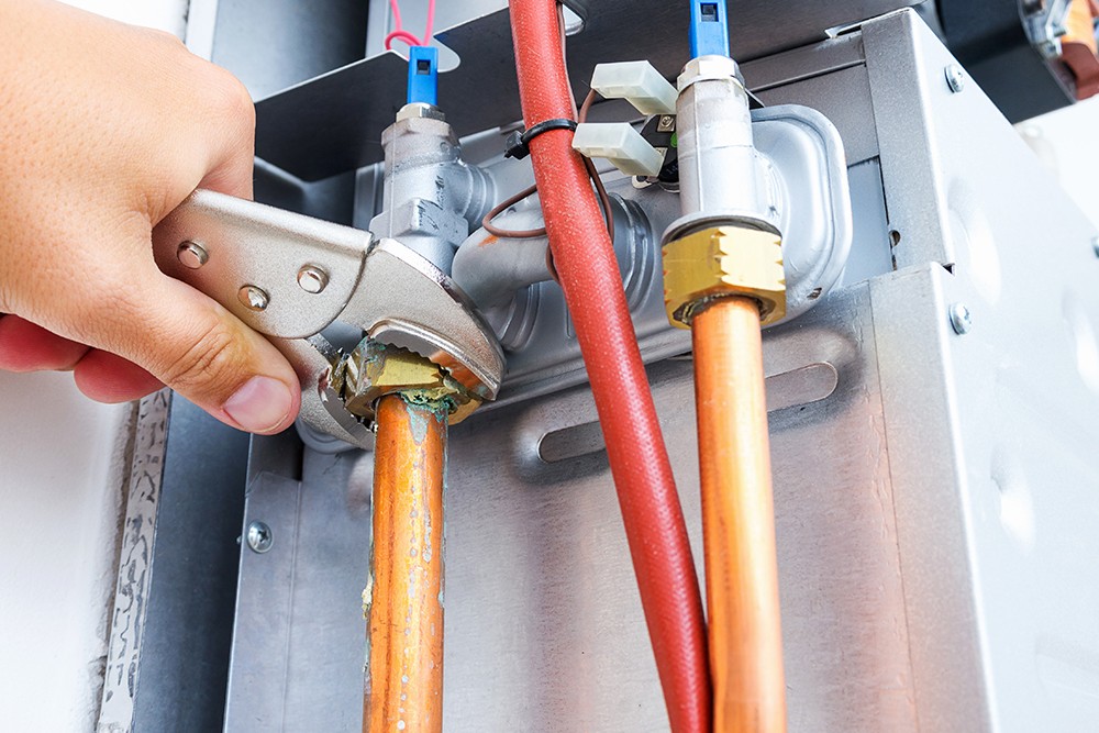Close up of hands using a screwdriver to repair internal workings of boiler water heater