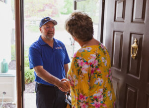 Lancaster Plumbing, Heating, Cooling & Electrical employee greets homeowner, shaking hands at the front door.