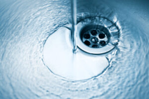 Water going down the drain in a stainless steel sink.