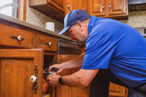 Technician inspecting pipes beneath sink in a home