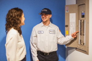 Smiling electrician shows homeowner the breaker panel in a house