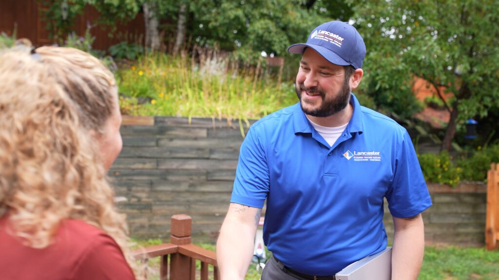 Lancaster Plumbing & Heating employee greeting a homeowner outside.