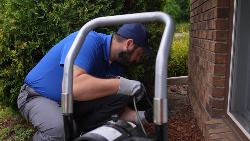 Lancaster technician inspecting a home's drain line outside.